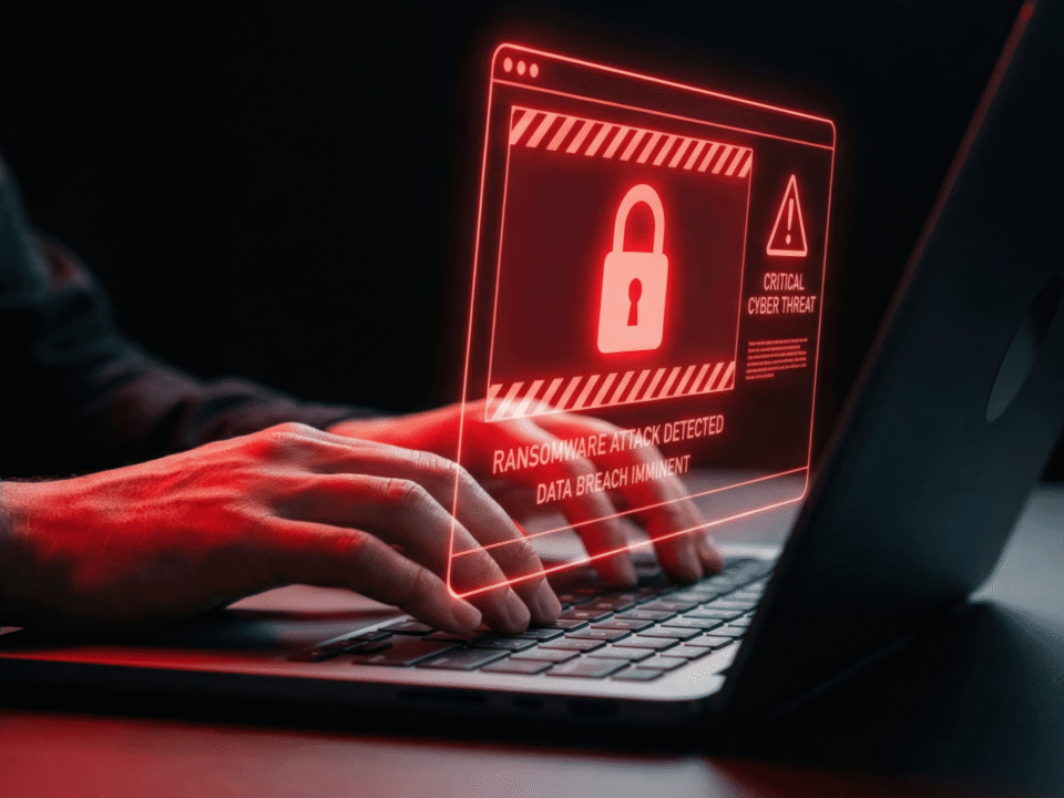 Hands typing on a laptop with a ransom warning dispaly