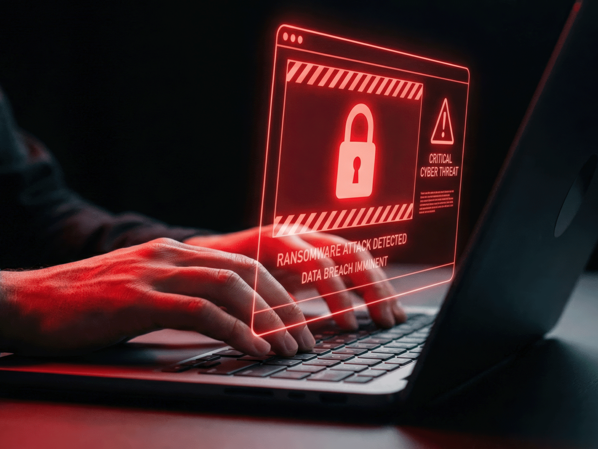 Hands typing on a laptop with a ransom warning dispaly