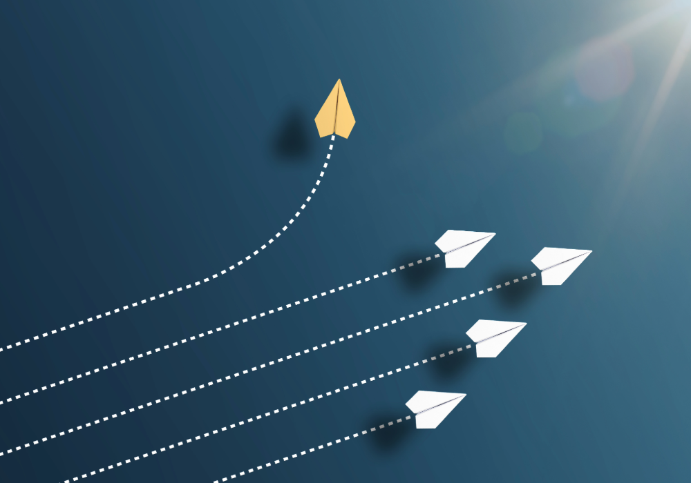 "Six paper airplanes on a blue background, with five white planes flying in formation to the right and one yellow plane curving upward to the left, symbolising innovation and individuality."