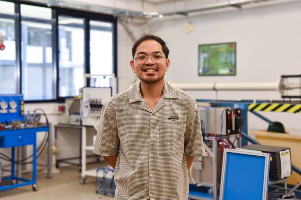 Engineering student standing in a lab with a short sleeve shirt