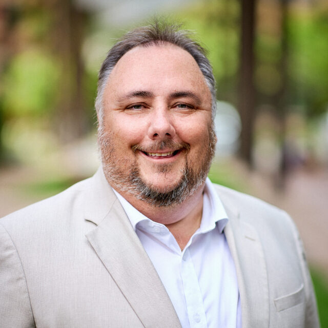 David Elkin Headshot - David wears a light coloured jacket and a white shirt, he has facial hair.