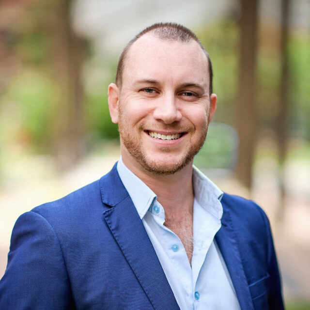 Ian Shepherd Headshot - Ian wears a blue shirt and blue jacket.