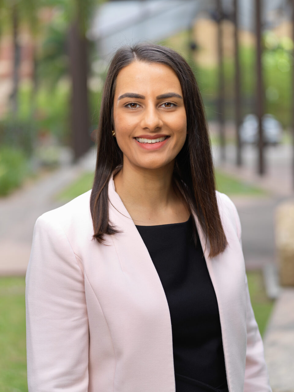 Mainaaz Oakley Headshot - Mainaaz wears a back shirt with a pink jacket.