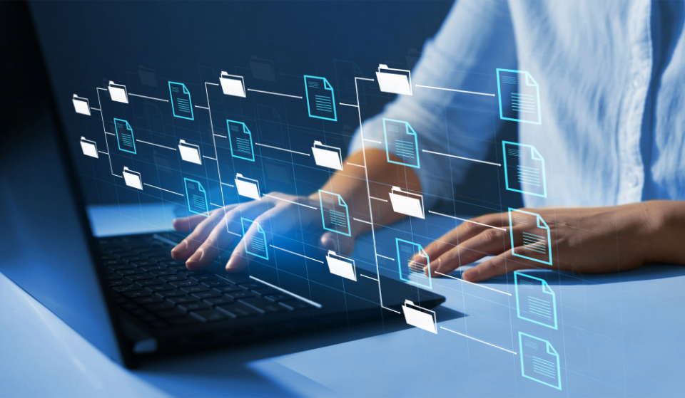 "Person using a laptop with a digital overlay of file and folder icons arranged hierarchically, representing digital file management and data organisation."