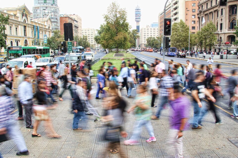 Busy street with traffic lights, pedestrians crossing and cars and buses in the backround