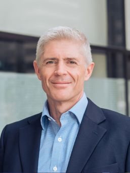 Neil Makepeace Headshot - Neil wears a blue shirt and a blue jacket